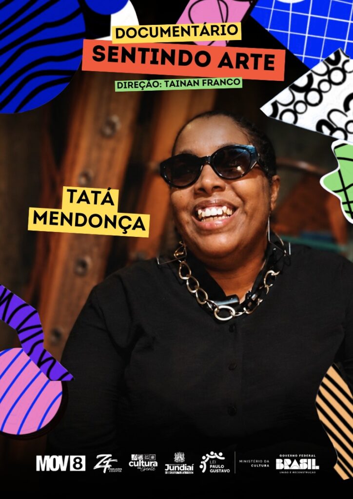 #PraCegoVer: Cartaz de divulgação do documentário “Sentindo Arte”. A imagem mistura fotografia e colagem gráfica, com formas abstratas coloridas nas bordas, em azul, rosa, verde, preto e branco. No centro, aparece uma mulher negra sorrindo, usando óculos escuros, camisa preta, colar grande e brincos. Ela está em um ambiente interno, com fundo desfocado em tons escuros e amadeirados. À esquerda da imagem, há uma faixa amarela com o nome “Tatá Mendonça” em letras pretas. Na parte superior, em faixas coloridas, está escrito “Documentário Sentindo Arte” e, abaixo, “Direção: Tainan Franco”. Na parte inferior, há uma faixa escura com os logotipos da MOV8, ZF Produções e Eventos, Cultura Jundiaí, Prefeitura de Jundiaí, Lei Paulo Gustavo, Ministério da Cultura e Governo Federal Brasil – União e Reconstrução.