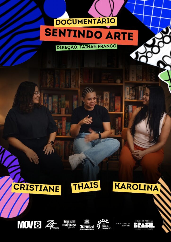 #PraCegoVer: Cartaz de divulgação do documentário “Sentindo Arte”. A imagem mistura fotografia e colagem gráfica, com formas abstratas coloridas nas bordas, em azul, rosa, verde, preto e branco. No centro, aparecem três mulheres sentadas, conversando em um ambiente interno. A mulher ao centro usa camiseta preta, calça jeans e tênis branco, e gesticula com as mãos enquanto fala. À esquerda, há uma mulher de roupa preta, olhando para ela; à direita, uma mulher de blusa branca e calça laranja, também voltada para a conversa. Na parte inferior da imagem, há três faixas amarelas com os nomes "Cristiane", "Thais" e "Karolina" em letras pretas. Ao fundo, há uma estante com jogos ou caixas coloridas. Na parte superior, em faixas coloridas, está escrito “Documentário Sentindo Arte” e, abaixo, “Direção: Tainan Franco”. Na parte inferior, há uma faixa escura com os logotipos da MOV8, ZF Produções e Eventos, Cultura Jundiaí, Prefeitura de Jundiaí, Lei Paulo Gustavo, Ministério da Cultura e Governo Federal Brasil – União e Reconstrução.